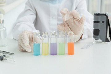 Test tubes with multi-colored liquids in front and blured hands of young scientist, preparations for chemical experinents.