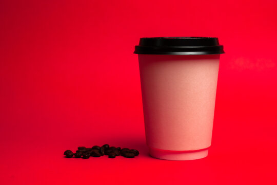 white paper cup with coffee beans on a red background