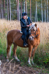 Woman horseback riding on a forest trail