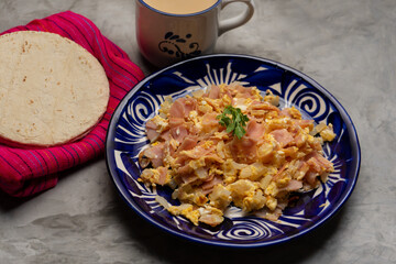 Scrambled eggs with ham for breakfast on grey background