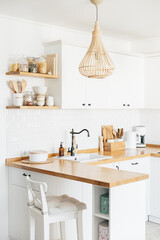 View of white modern country style u-shape kitchen interior with open shelving with various white...