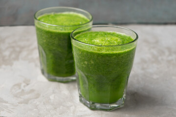 Green juice in glass on grey background