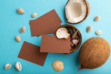 Brown paper business card with coconut and seashells on blue pastel background. top view, copy space.
