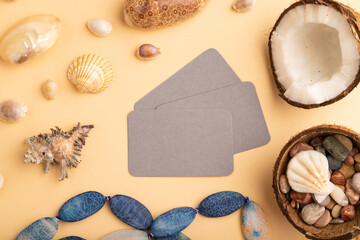 Fototapeta na wymiar Brown paper business card with coconut, seashells, pebbles, beads on orange pastel background. top view, copy space.