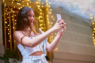 Young woman taking selfie with her mobile outside a restaurant.