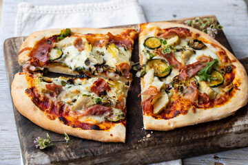 Home made pizza with artichokes, parma ham and zucchini
