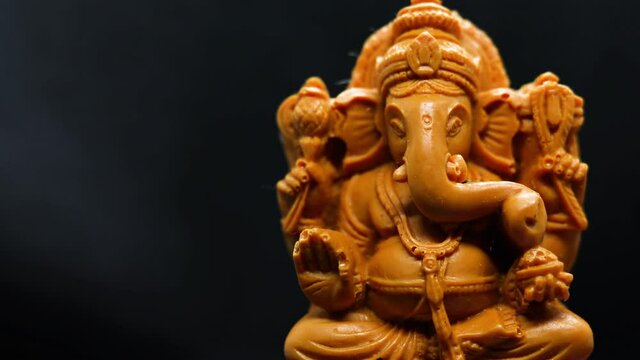 A multi-shaped holographic glow fell on the statue of the Hindu god Ganapati with a black background for the Tamil festival Ganesha Chaturthi concept.