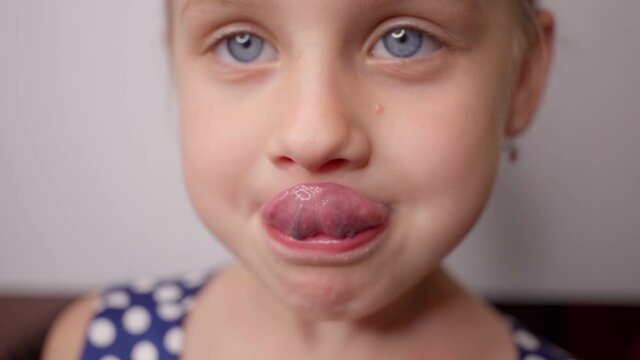 little girl trying to reach nose with his tongue, speech therapy exercises for speech development. from speech therapist. dentist. mouth, tongue is stuck out as far as possible
