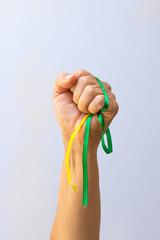 Holding green and yellow ribbons of Brazil flag isolated on white background. Flag and Independence Day Concept Image.