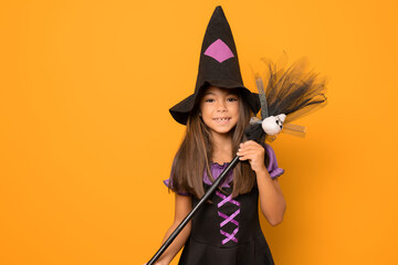 Beautiful little girl in Halloween costume isolated over orange background. Halloween, carnival,...