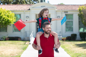 Obraz premium Father and son run with father after come back from school. School, family, education and outdoor concept, first day of fall. Dad and son having fun near school yard. Concept of friendly family.