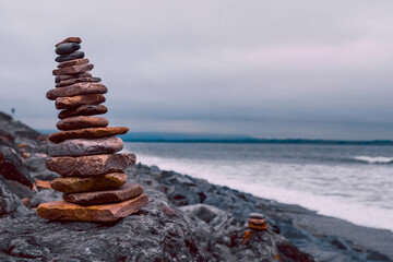 Fototapeta na wymiar Pyramid of stones by the ocean at blue hour