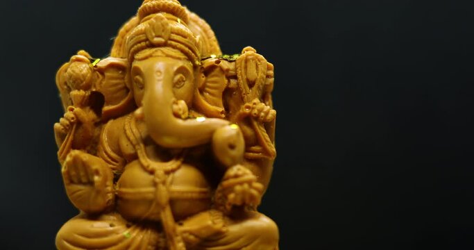 The golden glow fell on the statue of the Hindu god Ganapati with a black background for the Tamil festival Ganesha Chaturthi concept.
