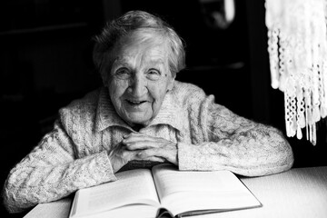 Portrait of an old woman reading a book. Black and white photo.