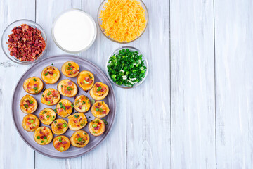 Red skinned loaded potatoes with crispy bacon, scallions and cheddar cheese, horizontal, top view, copy space