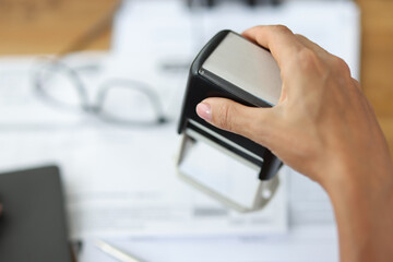 Woman puts stamp on document in office closeup