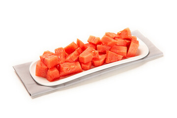 sandia cortada servida en una bandeja blanca sobre un paño de color gris claro