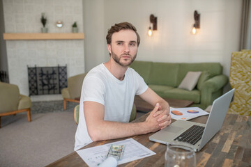 Young bearded man working on a laptop and looking concentrated