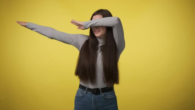 woman in gray turtleneck makes hype movement dab with her hands and covers her face. When you won or did everything right. Yes, I am very cool.