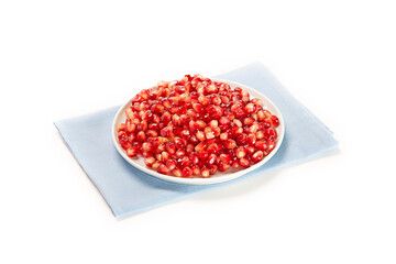 granos de granada en plato blanco sobre paño color azul claro fondo blanco