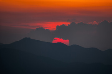 山と雲の隙間から現れた真っ赤な太陽