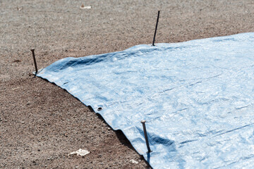blue tarpaulin with anchor spikes covering the pitcher's mound - obrazy, fototapety, plakaty
