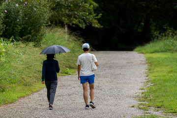 夏の公園でウォーキングしている男女の姿