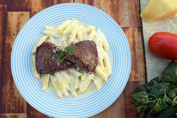 white sauce pasta and beef filet mignon with parmesan cheese, tomato, basil, herbs, delicious food from Italian and French cuisine