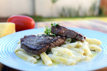 white sauce pasta and beef filet mignon with parmesan cheese, tomato, basil, herbs, delicious food from Italian and French cuisine