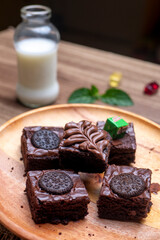 Chocolate Brownies on Wooden Plate with Fresh Milk as Background. Photographed on wooden table