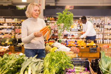 Mature woman buying fresh organic vegetables in supermarket