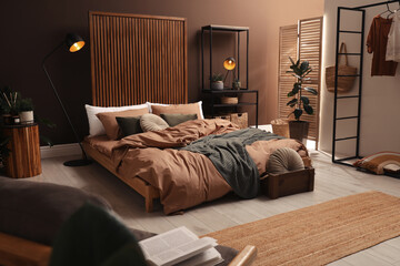 Stylish room interior with large bed near brown wall