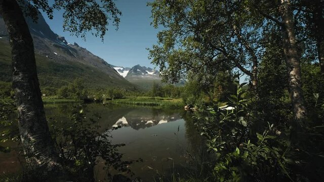 Revealing Shot Of A Boat Docked On The Lakeshore With Perfect Mountain Reflection On Lake Water. Innerdalen Nature Reserve In Norway.
