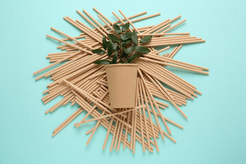 Naklejka na ściany i meble Paper cup with green twigs and bamboo straws on turquoise background, flat lay. Eco friendly lifestyle