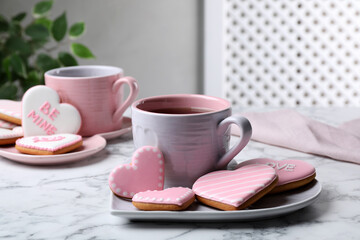 Delicious heart shaped cookies and cup of tea on white marble table