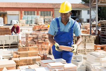 African man worker of a hardware store keeps records of ceramic paving slabs