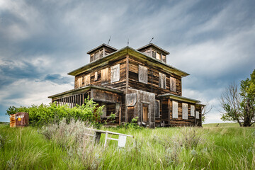 An old, abandoned home on the prairies of Saskatchewan with a crib in the foreground