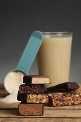 Different energy bars, protein cocktail and powder on wooden table