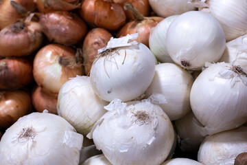 Two piles of white onions and traditional golden onions at a grocery store, lined-up, soft-focus in London, Canada. Produce, healthy cooking, flavouring ingredient, eye-watering vegetable.