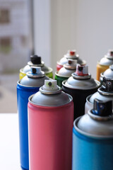 Cans of different graffiti spray paints on table, closeup