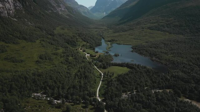 Mountain Lodge On The Lakeshore Meadow With Dense Foliage In Innerdalen Valley In Norway. aerial reveal