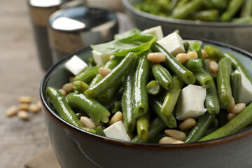 Delicious salad with green beans, pine nuts and cheese on table, closeup
