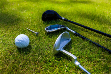 Golf clubs and ball lie on green grass in a rays of the everlasting sun. High quality photo
