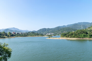 Fototapeta na wymiar Blue sky, green mountains and trees surround the lake