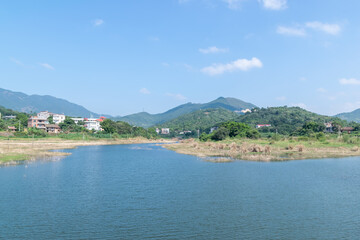 Blue sky, green mountains and trees surround the lake