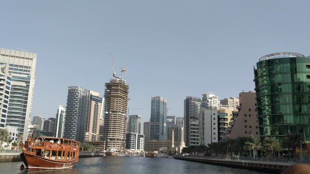 Touristic yacht trip in Dubai Marina. Construction work, hotels and skyscrapers viewed from the canal.