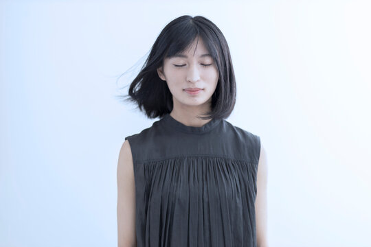 髪をなびかせて目を閉じる若い日本人女性