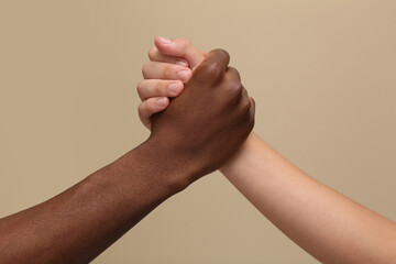 Men clasping hands on beige background, closeup