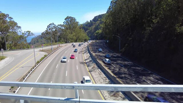 Locked shot of winding highway traffic from overpass on a blue sky day