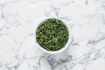 Aromatic thyme in bowl on white marble table, top view - obrazy, fototapety, plakaty